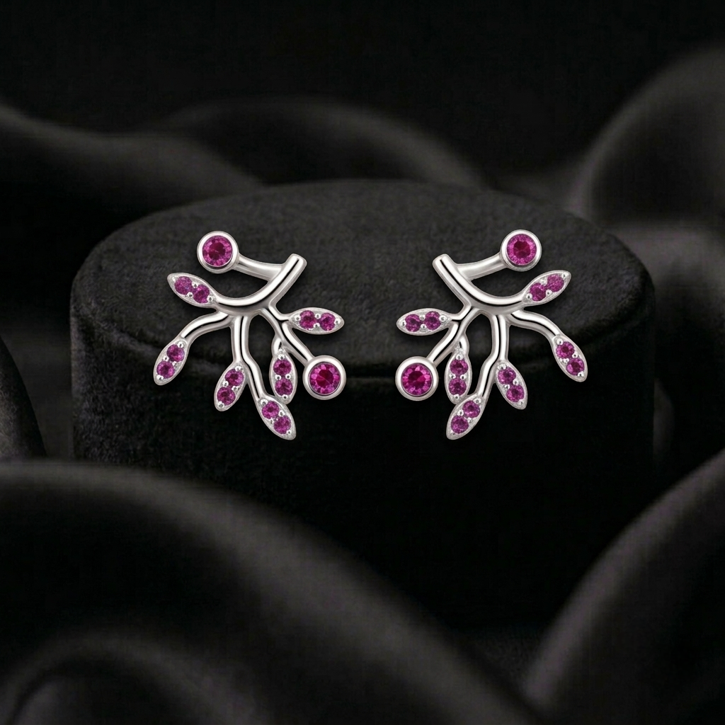 A pair of 925 sterling silver branch-shaped stud earrings set with small round pink stones by Chakore, displayed on a black velvet jewellery stand against a dark draped fabric background.