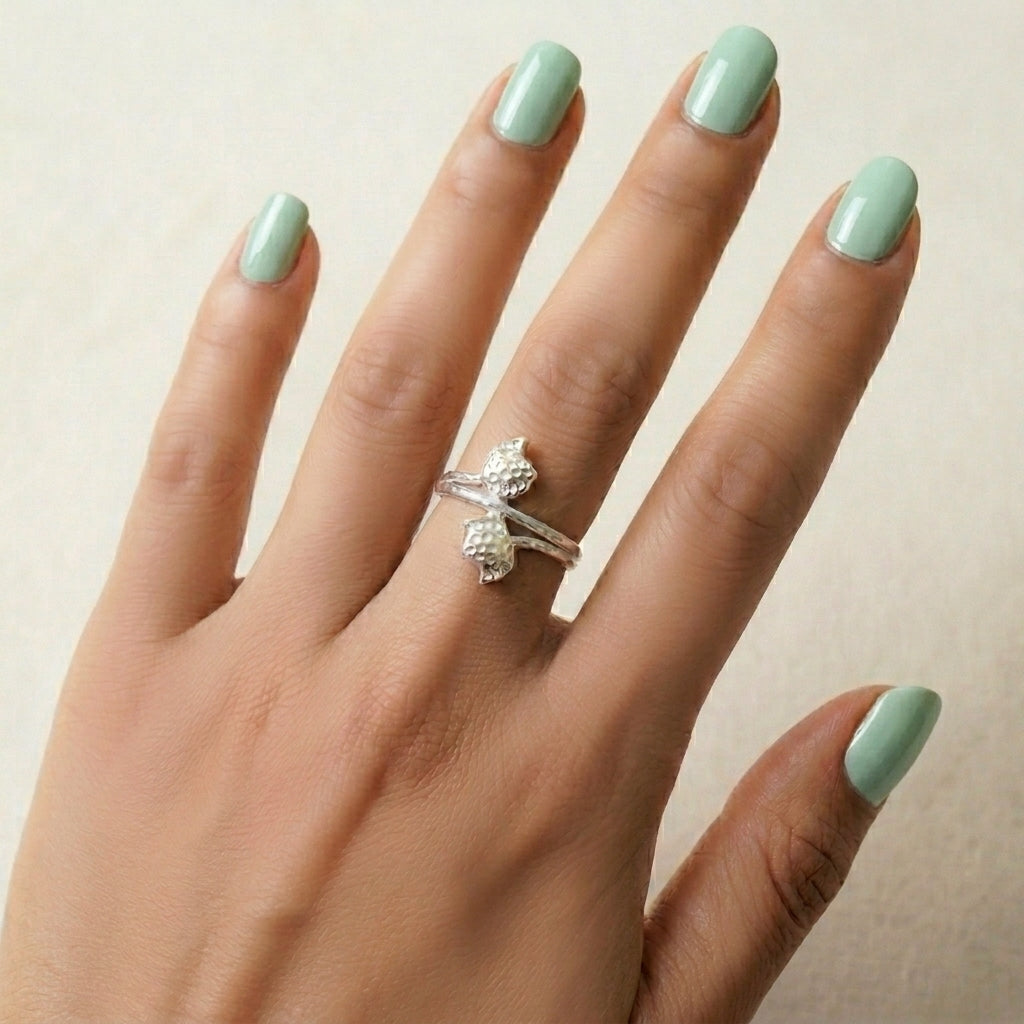 Hand with  double tulip flower 925 sterling silver ring by CHAKORE and mint green nails on a neutral background