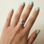 Hand with  double tulip flower 925 sterling silver ring by CHAKORE and mint green nails on a neutral background