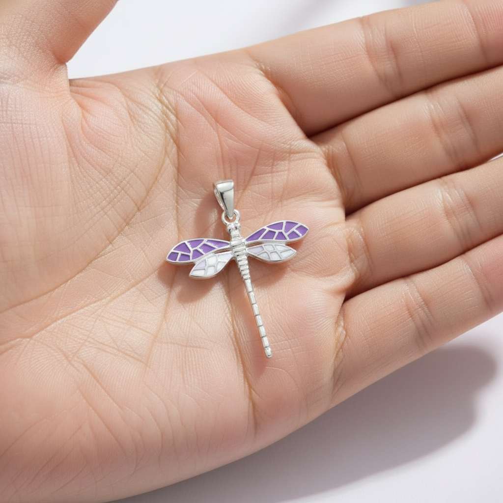 A close-up photograph of a standalone 925 sterling silver dragonfly pendant featuring intricate purple and soft blue segmented wings. The high-polish pendant features a smooth top loop, resting gracefully on a hand's palm. Minimalist Indian D2C jewelry, nature-inspired pendant, everyday modern styling.

