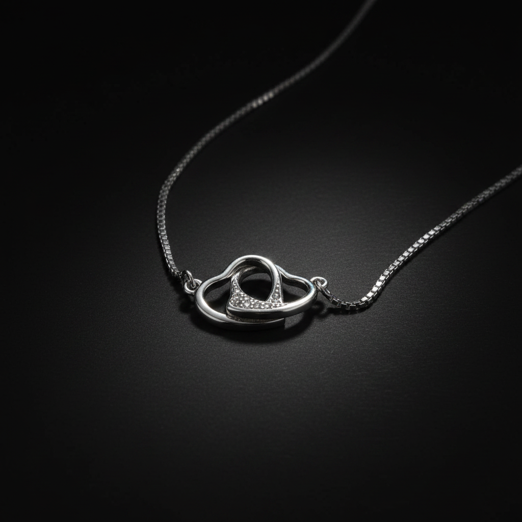925 sterling silver free-moving interlocked open hearts necklace dramatic single-light studio shot on dark charcoal background – high contrast luxury fine jewelry editorial
