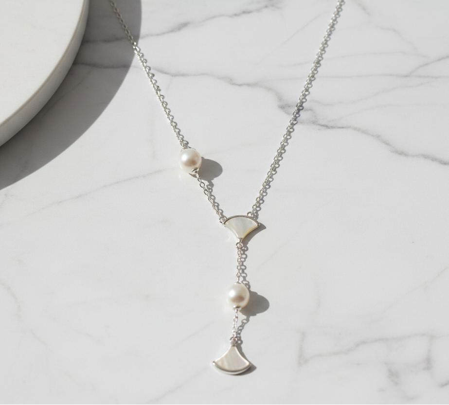Asymmetric 925 silver Necklace by CHAKORE with pearls and GinkgoFan leaves pendants on Flat Lay on Marble