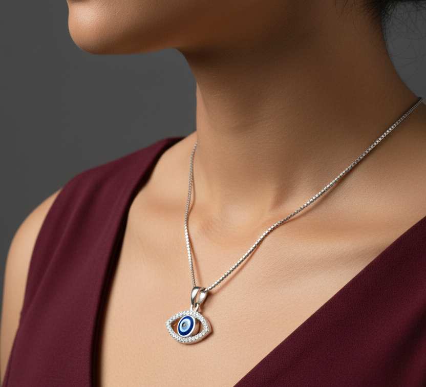 925 sterling silver evil eye pendant necklace worn at neckline, sideways profile pose on Indian model in burgundy dress, jewelry editorial close-up