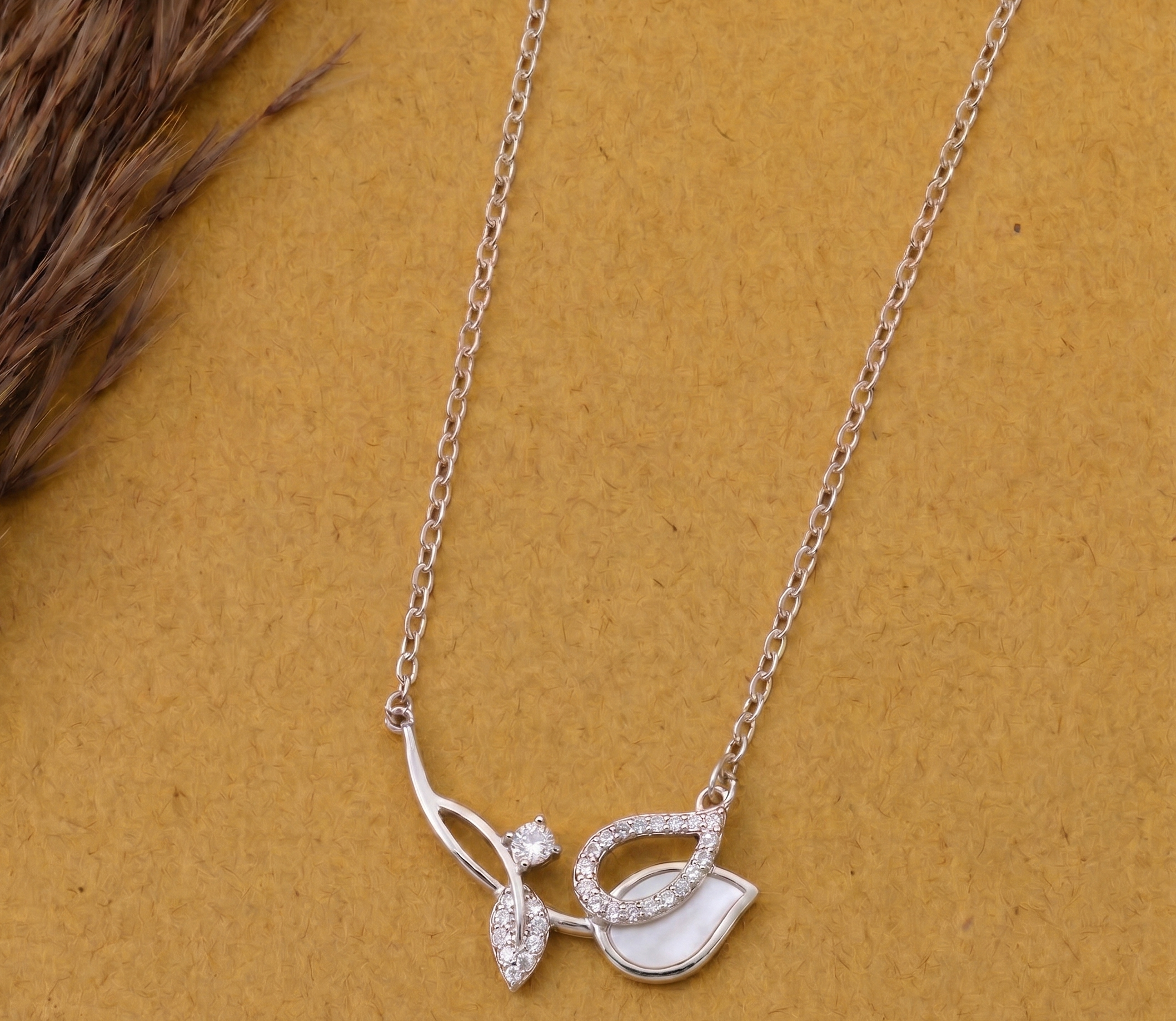 925 Sterling Silver asymmetrical leaf necklace by  CHAKORE on a mustard background