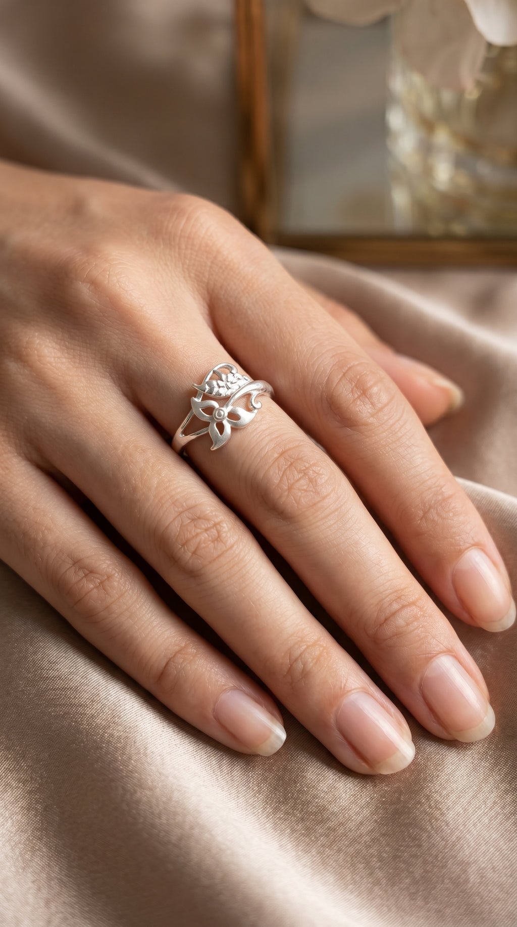 925 Sterling Silver Botanical Wrap ring by CHAKORE on hand wearing a silver ring with intricate design on a soft fabric background.