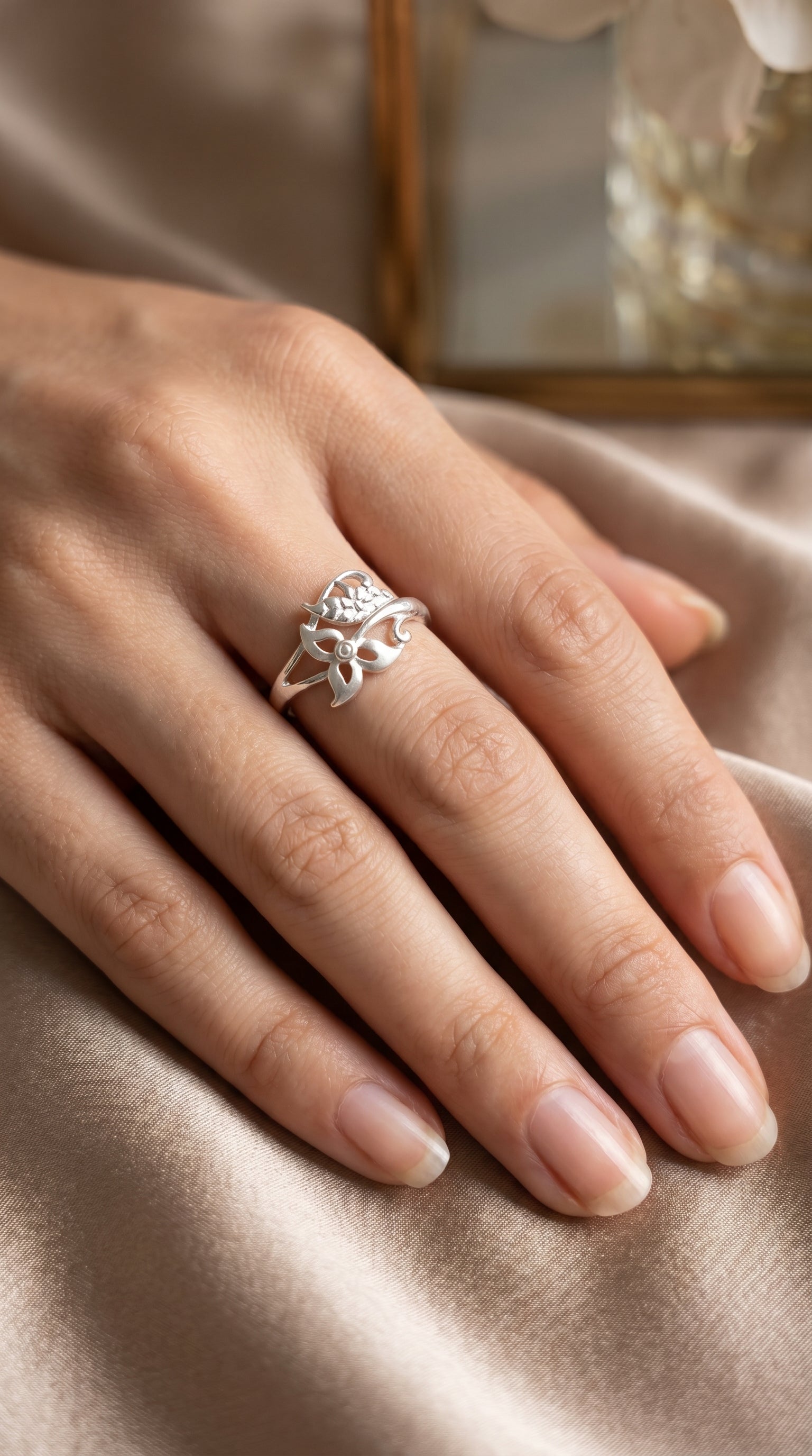 925 Sterling Silver Botanical Wrap ring by CHAKORE on hand wearing a silver ring with intricate design on a soft fabric background.