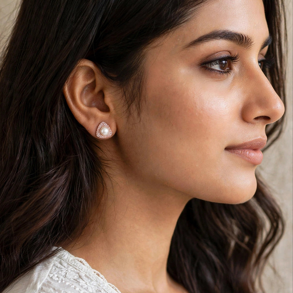 A close-up side profile of a woman wearing a small teardrop-shaped pearl stud earring with a gold-toned setting.