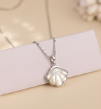 925 Silver necklace with a shell pendant on a light pink ribbon against a beige background