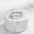 Crossover Infinity 925 Sterling Silver Ring by CHAKORE with Pavé Cubic Zirconia – Adjustable Band on Marble pedestal flat lay
