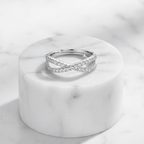 Crossover Infinity 925 Sterling Silver Ring by CHAKORE with Pavé Cubic Zirconia – Adjustable Band on Marble pedestal flat lay