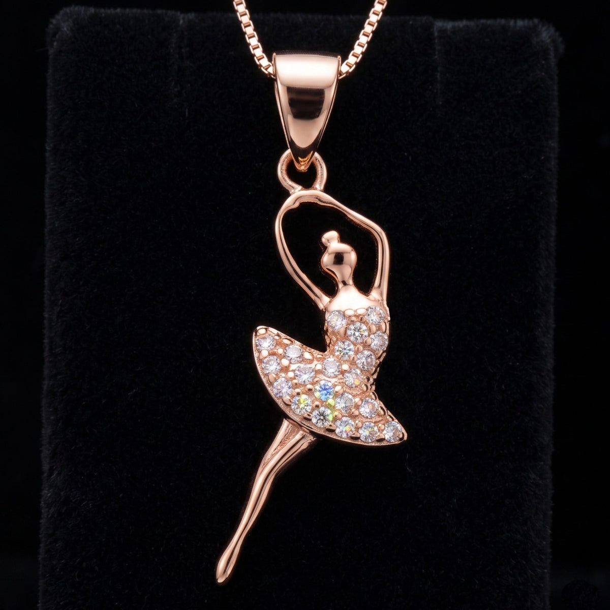 A 925 sterling silver ballerina pendant necklace by chakore adorned with clear crystals, displayed on a black velvet jewelry stand against a black background.