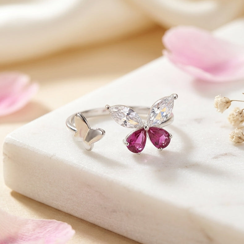 925 Sterling silver open butterfly ring by CHAKORE with  Butterfly-shaped ring with pink CZ on a marble surface with pink petals.