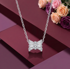 A modern 925 sterling silver necklace featuring a stylized Damru pendant crafted from sparkling baguette-cut cubic zirconia stones with a pavé center. The elegant spiritual Hindu jewelry is suspended over a rich burgundy geometric background, accented with soft pink and deep purple roses. Modern Indian D2C silver jewelry, Shiva Damru necklace, high-polish rhodium finish.