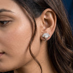 A close-up side profile of a woman wearing a small 925 silver stud earring with a clear faceted real freshwater pearl on a dark blue background.