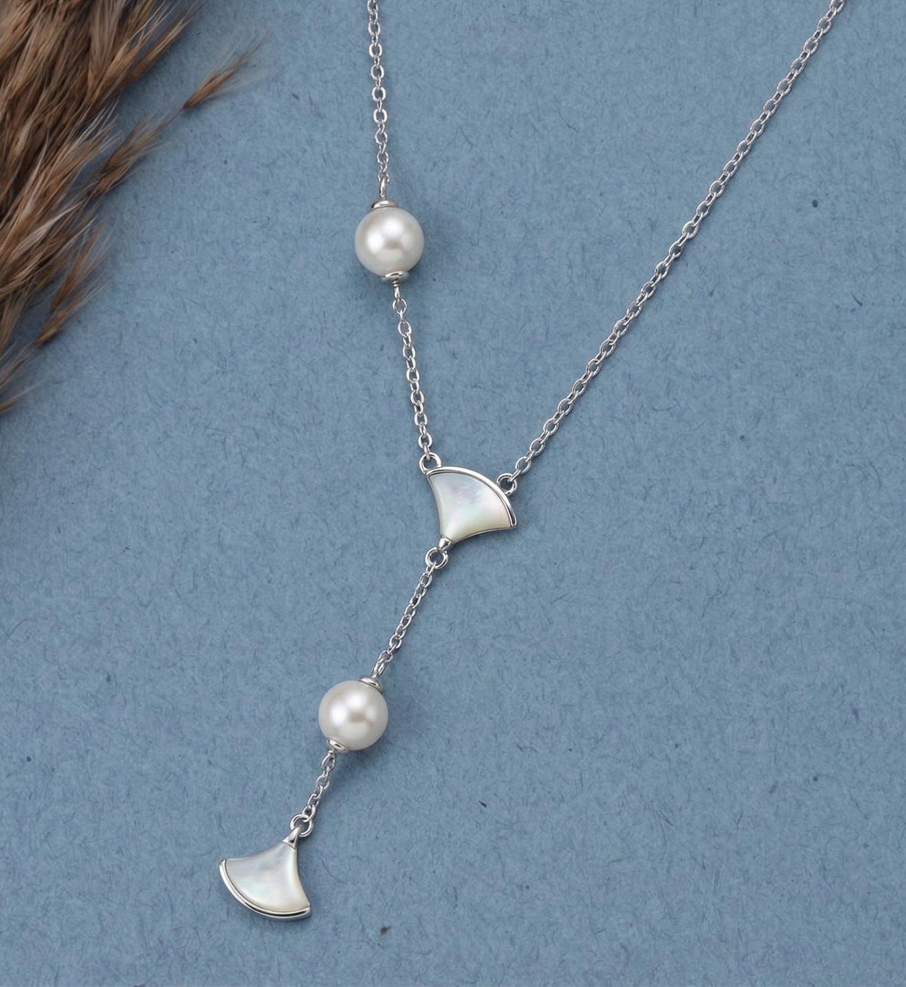 Asymmetric 925 silver Necklace by CHAKORE with pearls and GinkgoFan leaves pendants on a blue background