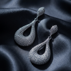 Pair of 925 sterling silver teardrop earrings on black satin fabric with text about elevated evening comfort.