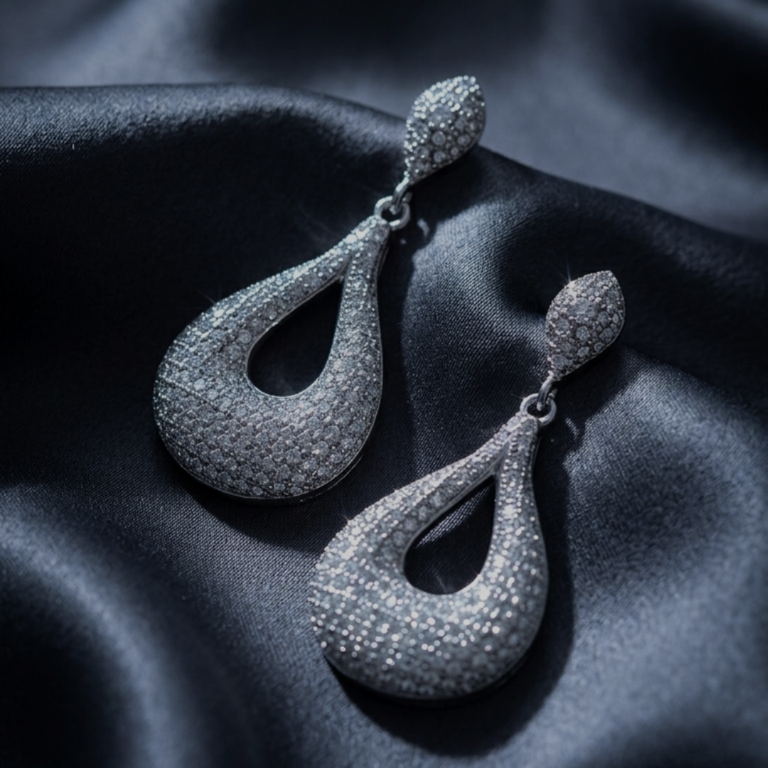 Pair of 925 sterling silver teardrop earrings on black satin fabric with text about elevated evening comfort.