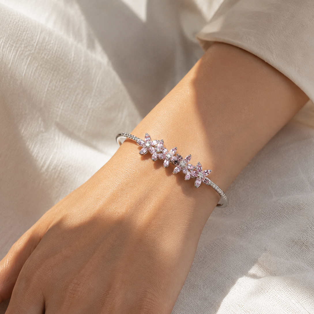 Model wearing Chakore 925 sterling silver open cuff bracelet with four pink floral CZ clusters, styled in natural sunlight for an elegant everyday luxury look.