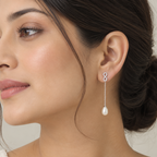 A close-up of a woman wearing a delicate 925 silver drop earring by Chakore with high grade small CZ stones infinity and a white teardrop freshwater pearl, shown against a soft beige background.