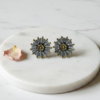 Oxidised 925 silver stud earrings with brass gold flower centre displayed on elevated white marble platform, minimal styling — CHAKORE premium silver jewellery