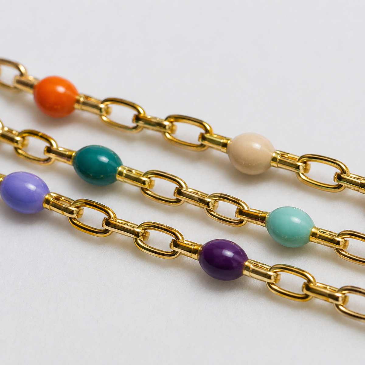 Macro close-up of the Chakore 925 sterling silver vibrant triple layer gold bracelet showing colorful enamel beads, gold-plated chain links, smooth enamel finish, and evenly spaced bead detailing