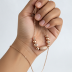 Rose gold beaded 925 silver necklace held between fingers for size reference, minimalist white background