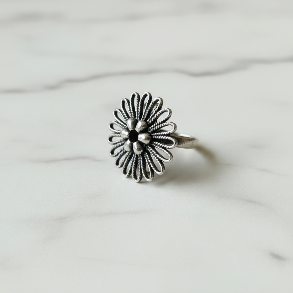 Oxidised sterling silver filigree flower ring at 45 degree angle showing face and band, handcrafted twisted wire detail, white background