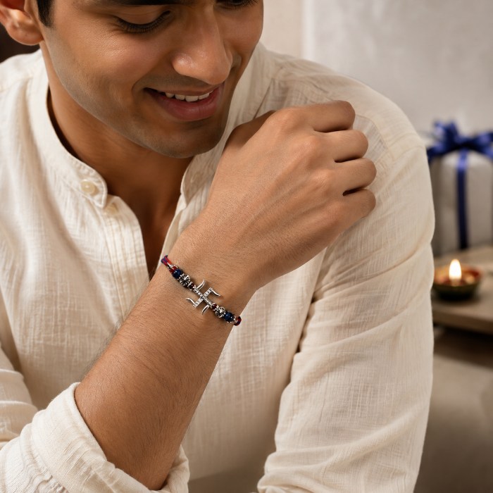 Close-up of a young Indian man wearing the Chakore Swastik Silver Rakhi with a genuine 925 sterling silver Swastik pendant, paired with a traditional cream kurta in an elegant Raksha Bandhan lifestyle setting.