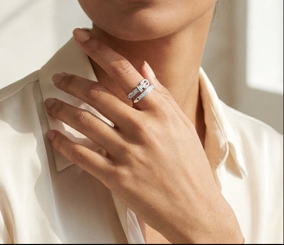 Woman wearing a white shirt with a trendy belt 925 silver on her finger, standing in a softly lit room.